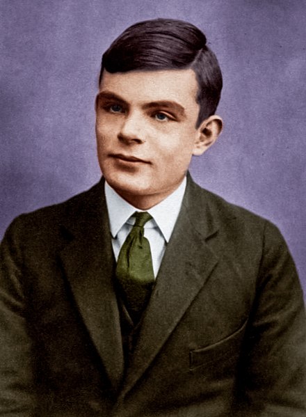 A colorized portrait of Alan Turing at the age of 16, wearing a dark green suit and tie with a white shirt. His neatly combed dark hair frames his youthful face, which bears a slight, thoughtful expression. Purple background.