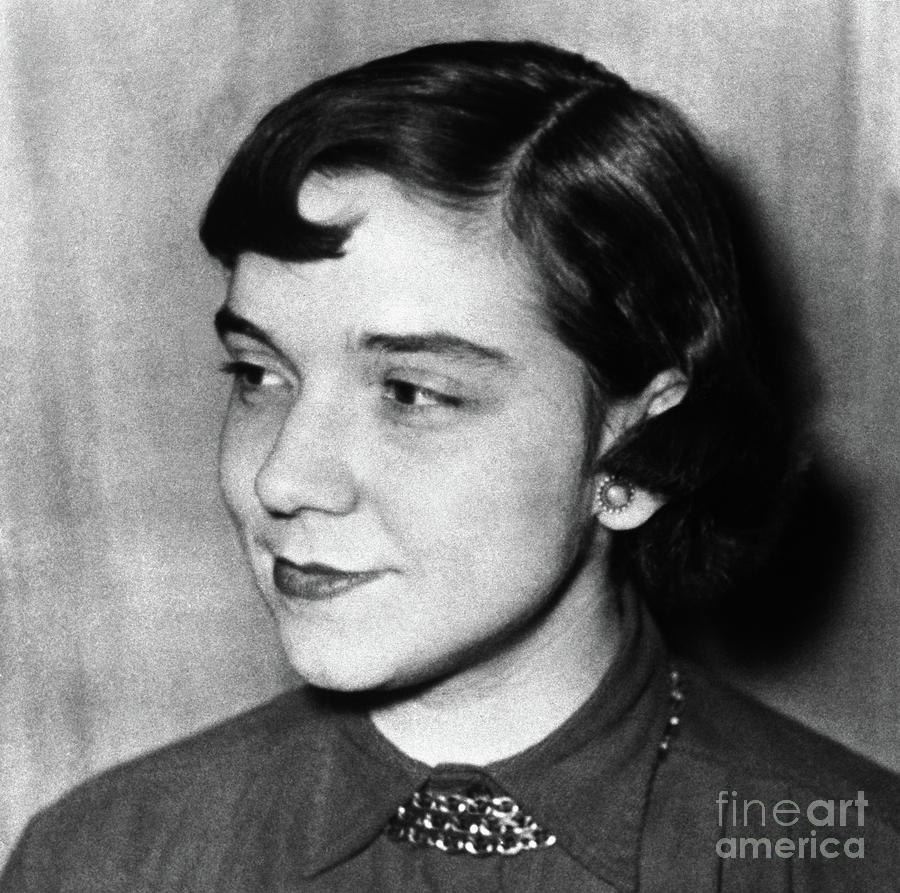 Black-and-white portrait of a young Adrienne Rich looking off to the side with a composed expression. Her hair is styled in soft waves, and she is wearing a collared blouse with a decorative necklace and stud earrings, reflecting a classic and refined style.