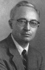 A later-life portrait of Alan L. Hart, showing him with graying hair and wearing a dark suit with a striped tie. He has a serious yet calm expression, looking directly at the camera.