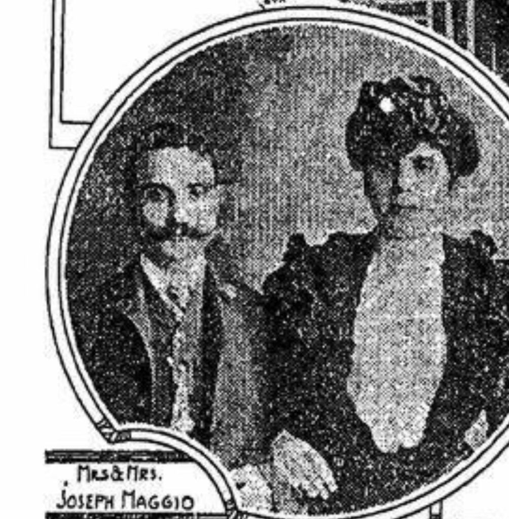 Black-and-white vintage photograph of Joseph and Katherine Maggio seated together. Joseph has a mustache and wears a suit and tie, while Katherine wears a dark dress with puffed sleeves and a large hat. The image is framed in an oval with a label reading “Mrs. & Mrs. Joseph Maggio.”