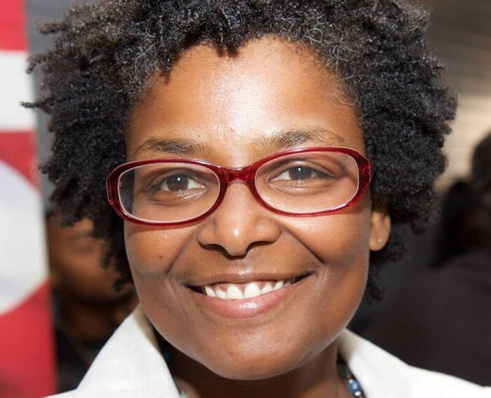 Close-up of Mary L. Washington at a public gathering, smiling, with red glasses and a white-collared top.