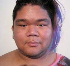 A close-up of CallOutQueen gazing directly into the camera with a neutral expression. Her hair is shaved on one side with purple highlights flowing to the other, and she wears a sleeveless top that reveals her bare shoulders.